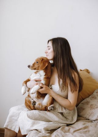 Woman holding beagle dog and sitting on couch