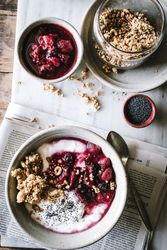 Delicious breakfast bowl with quinoa, rice and groats near tea cup and newspaper