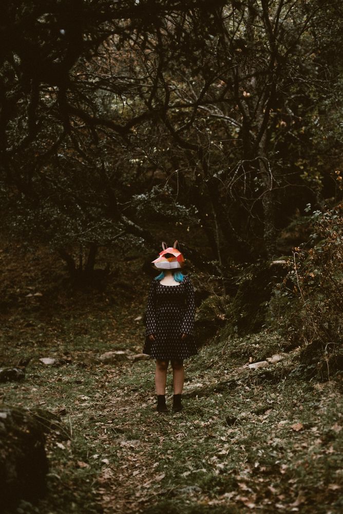 Woman in red fox mask walking in forest