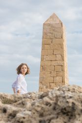 Young woman near brick monument and blue sky