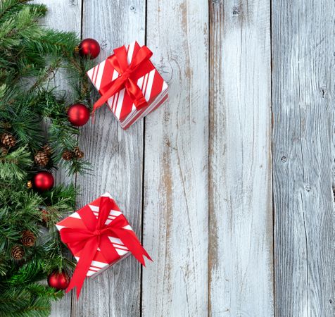 Christmas background with evergreen branches and red ornaments on aged wood