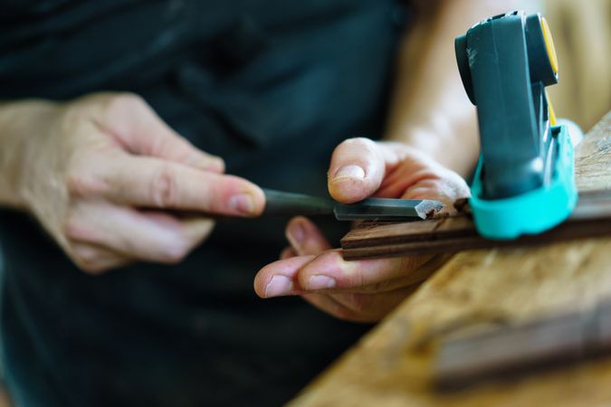 Man shaving guitar on workbench in luthier workshop