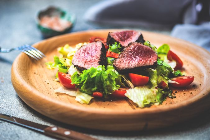 Delicious steak salad with fresh lettuce on wooden plate