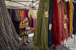 Happy customer standing under tent selling Merino wool products at a farmers market