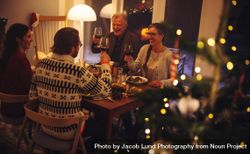 Family toasting wine and enjoying dinner on Christmas eve at dinner table bedDE4