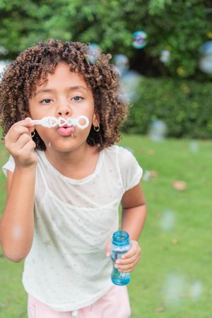 Little girl blowing bubbles in field