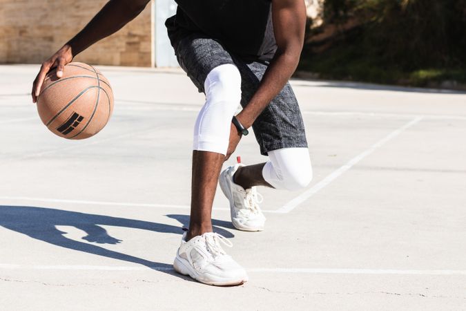 Anonymous Black man playing basketball on sports ground
