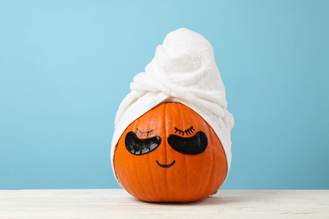 Pumpkin with towel and under eye patches against blue background