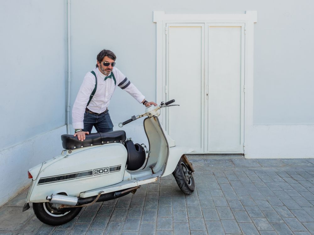 Trendy man sitting on vintage scooter