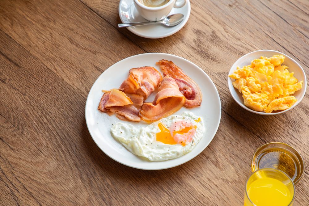 Tasty bacon and eggs with juice at table