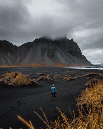 Person walking on soiled field in Stokksnes, Iceland