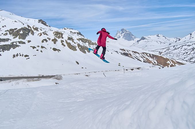 Unrecognizable snowboarder jumping on slope
