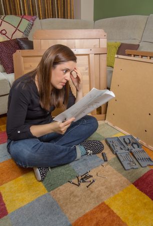 Woman reading instructions to assemble furniture
