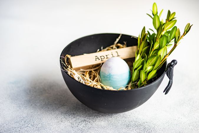 Easter card concept with bowl on table with colorful egg in straw
