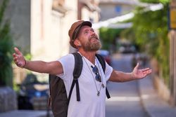 Smiling bearded man standing on street with outstretched arms
