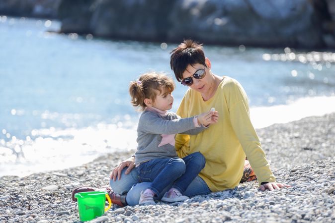 Short haired woman and little girl playing on a rocky beach
