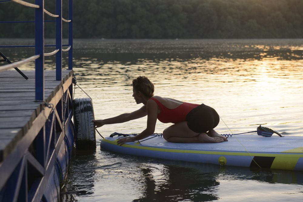 Woman launching from pier on paddleboard in the sunrise