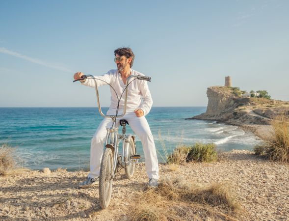 Man cycling on sandy beach hill