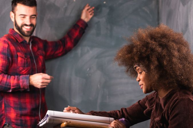Multiracial teacher and pupil in classroom at math lesson