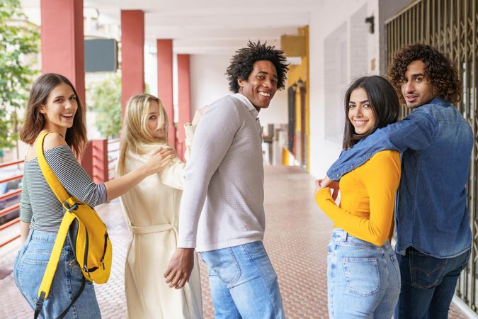 Multi-ethnic group of young people turning around looking at camera and smiling