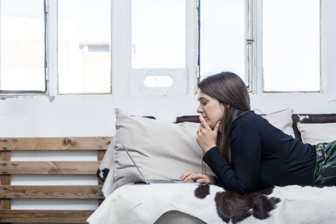 Woman lying on sofa in front of laptop