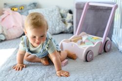 Happy baby near toy cart and blocks on bed