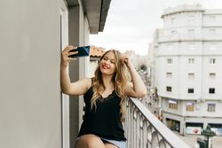 Young smiling female taking selfie on terrace