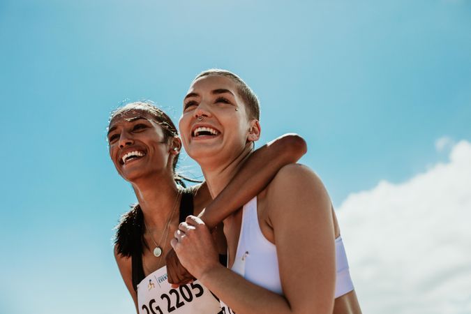 Two young woman athletes smiling outdoors