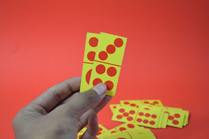 Person holding domino cards on red table
