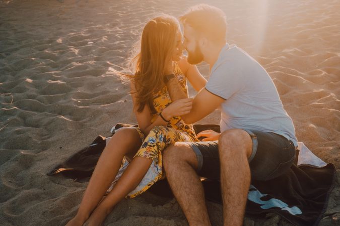 Tender couple kissing in sunlight on beach
