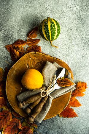 Top view of fall table setting with orange yellow leaves and squash on stone background