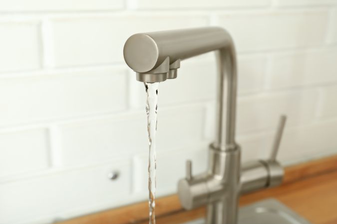 Kitchen water mixer with flowing water in kitchen room