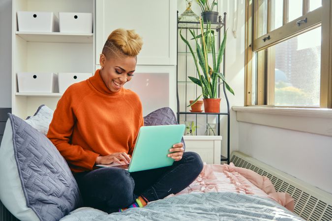 Smiling Black woman with a laptop in a bright modern home