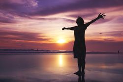 Person with arms outstretched at the beach