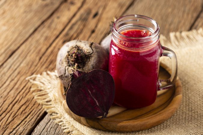Red beet juice in a glass cup on the wooden table.