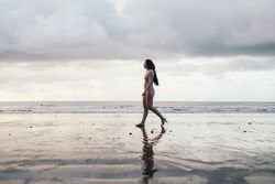 Brunette woman in bikini walking on the beach