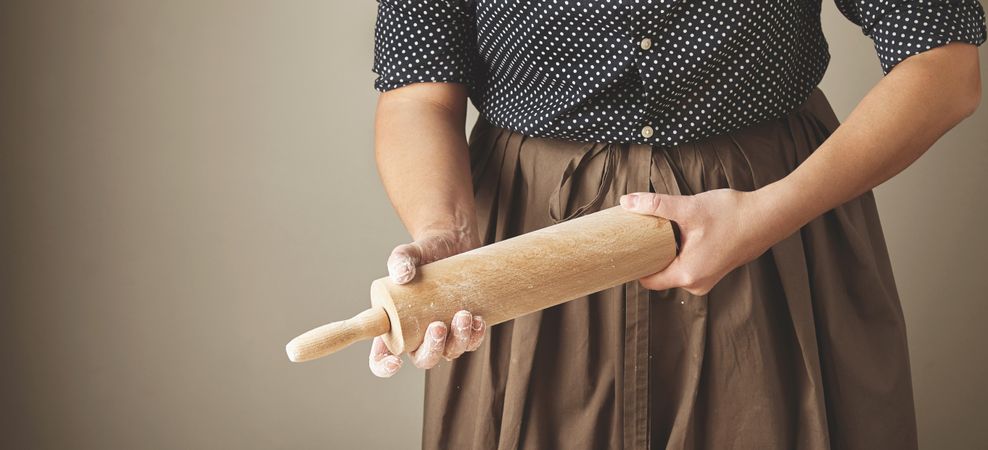 Woman holding rolling pin with flour on her hands