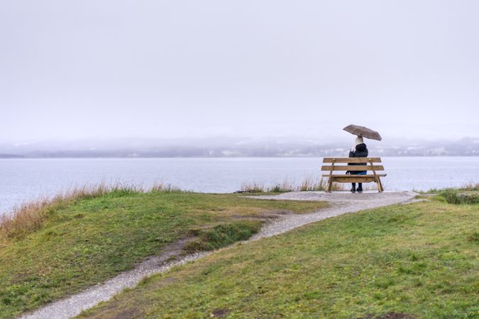 Woman sitting under umbrella on coast