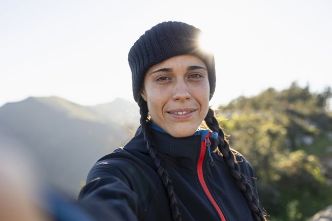 A young woman, mountaineer, in a hat takes a selfie while enjoying the scenery and nature
