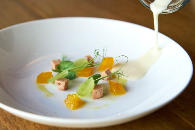 Celery cream in a jar poured into a plate with decorative ingred