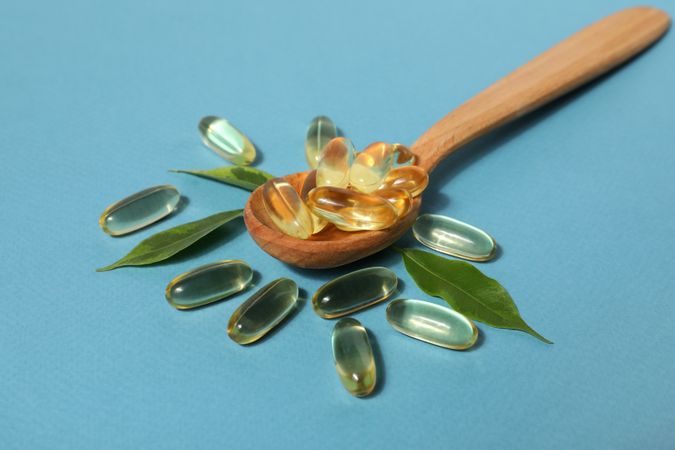 Wooden spoon with omega pills and leaves