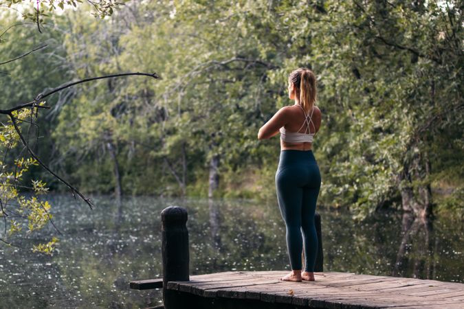 Woman in sportswear doing yoga outdoors near a lake