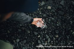 Hand holding ice on top of dark rocks 5aZMG4