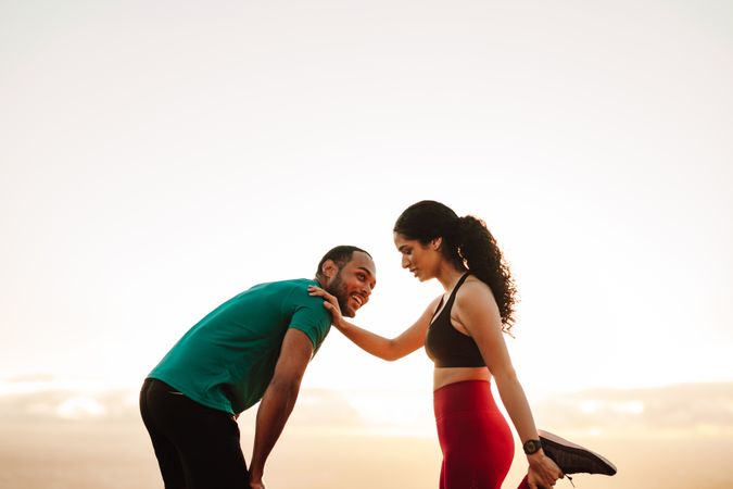 Cheerful fitness couple exercising standing outdoors