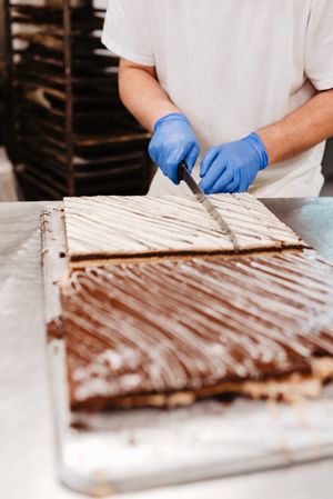 Anonymous cook cutting cake on table
