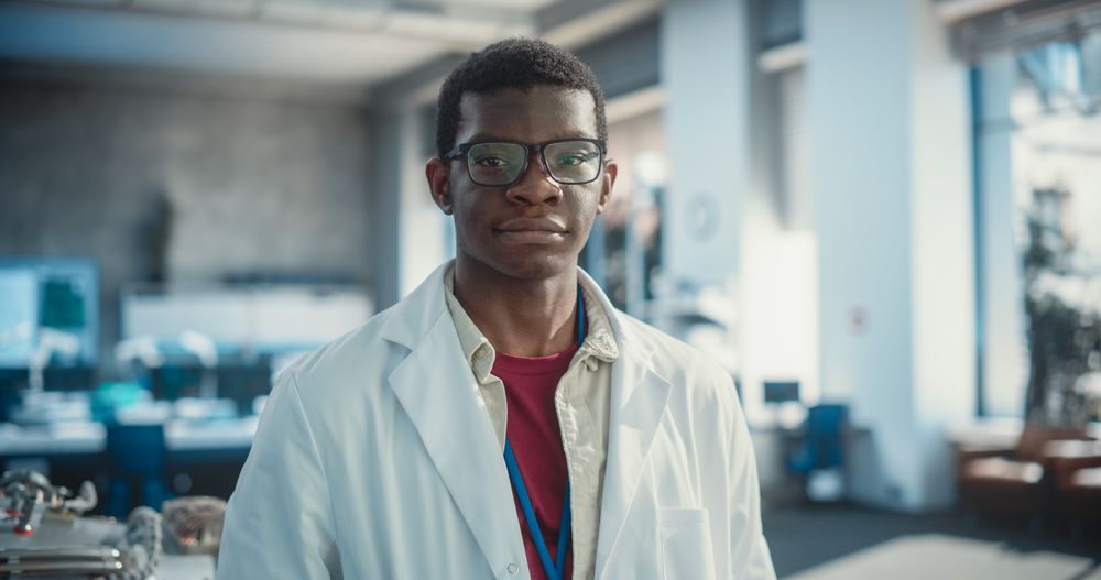 Portrait of Young Black Man Wearing Glasses and a Lab Coat Looking at the Camera.