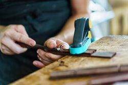 Male hands creating bridge of guitar in wood