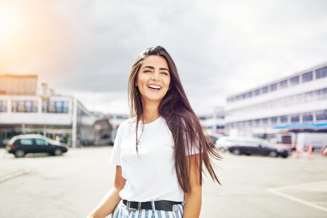 Radiant smiling woman outside in parking lot on overcast day with copy space