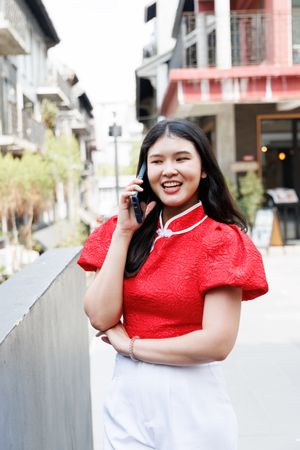 Smiling Asian woman talking on mobile phone standing in the city