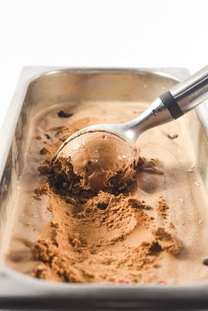 Scooping out a ball of brown chocolate chip ice cream